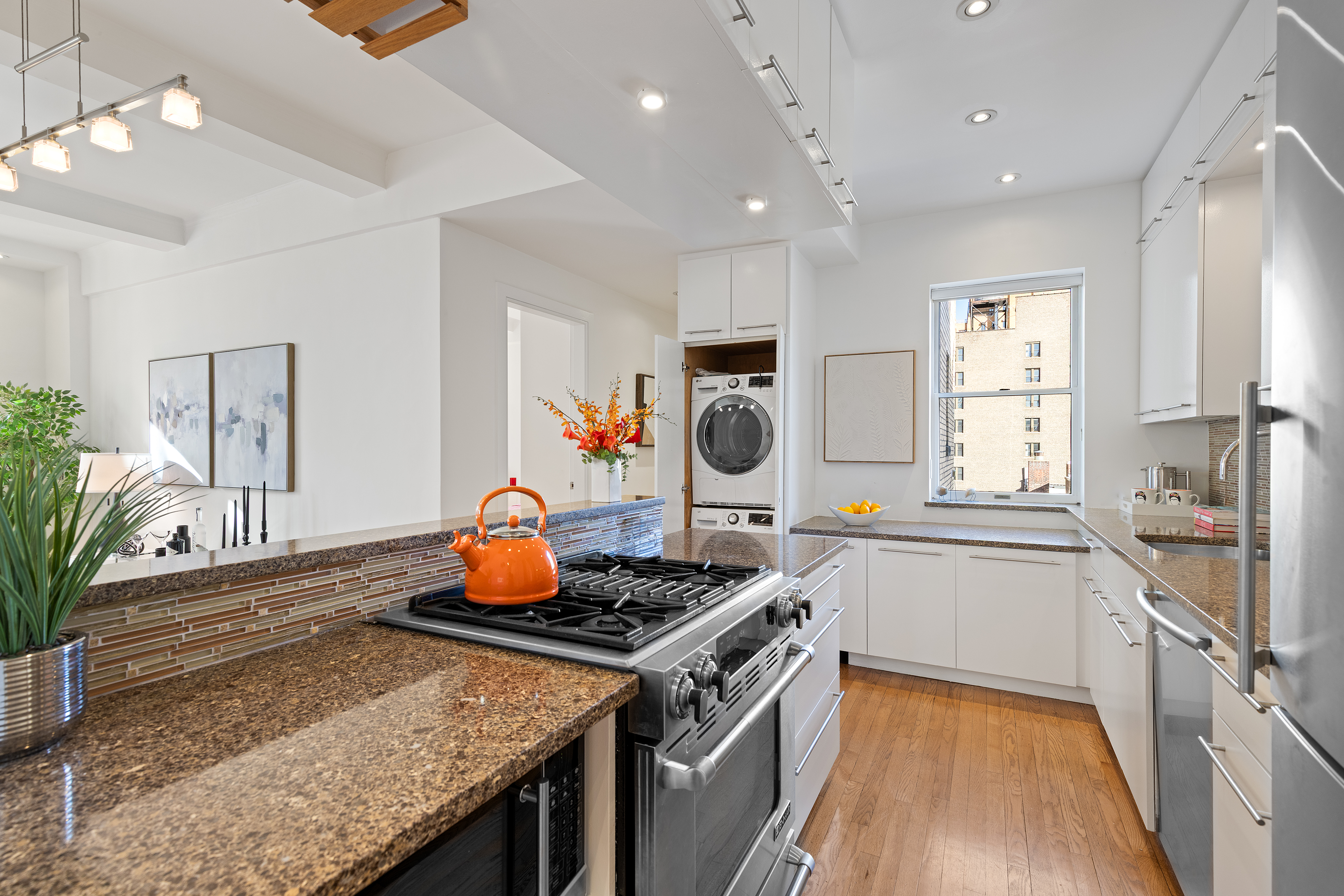 59 West 71st Street, Unit 9C Manhattan, NY 10023 - Photo 4 of 11 a kitchen with a stove a sink dishwasher and a dining table with wooden floor