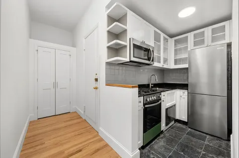 a kitchen with stainless steel appliances a refrigerator a stove and white cabinets