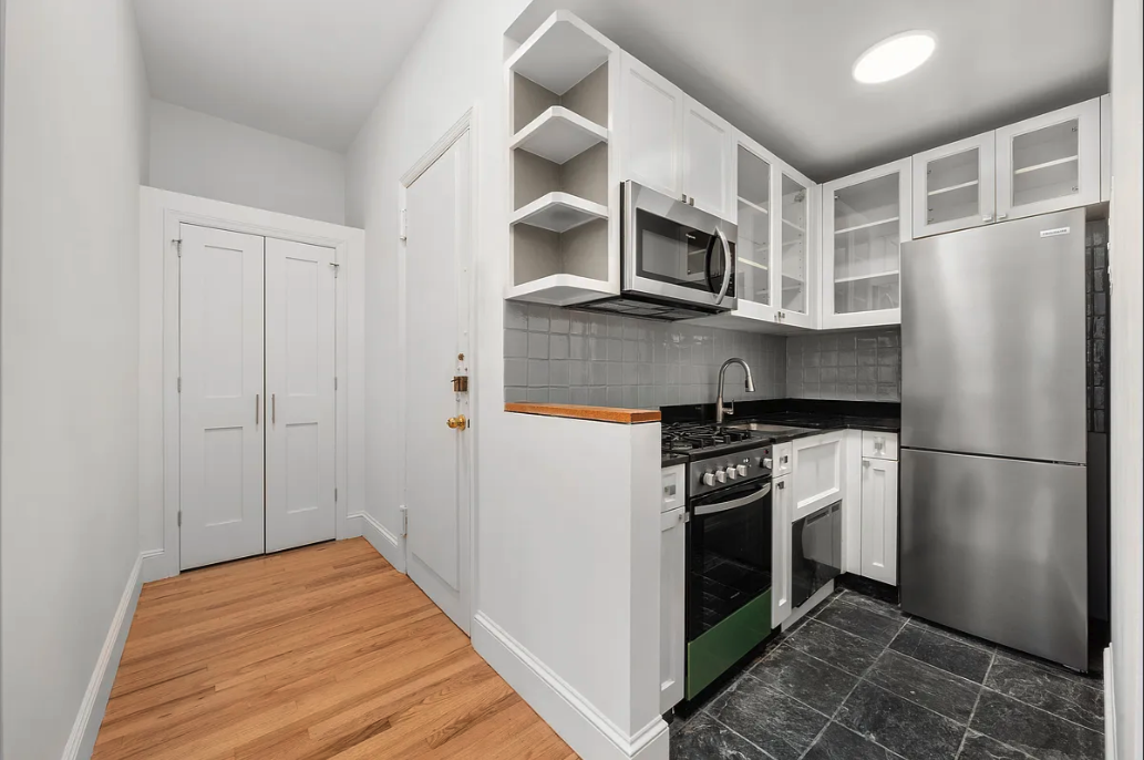 130 West 80th Street, Unit 4F Manhattan, NY 10024 - Photo 4 of 7 a kitchen with stainless steel appliances a refrigerator a stove and white cabinets