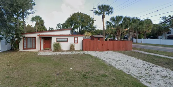 a view of a house with a yard and palm trees