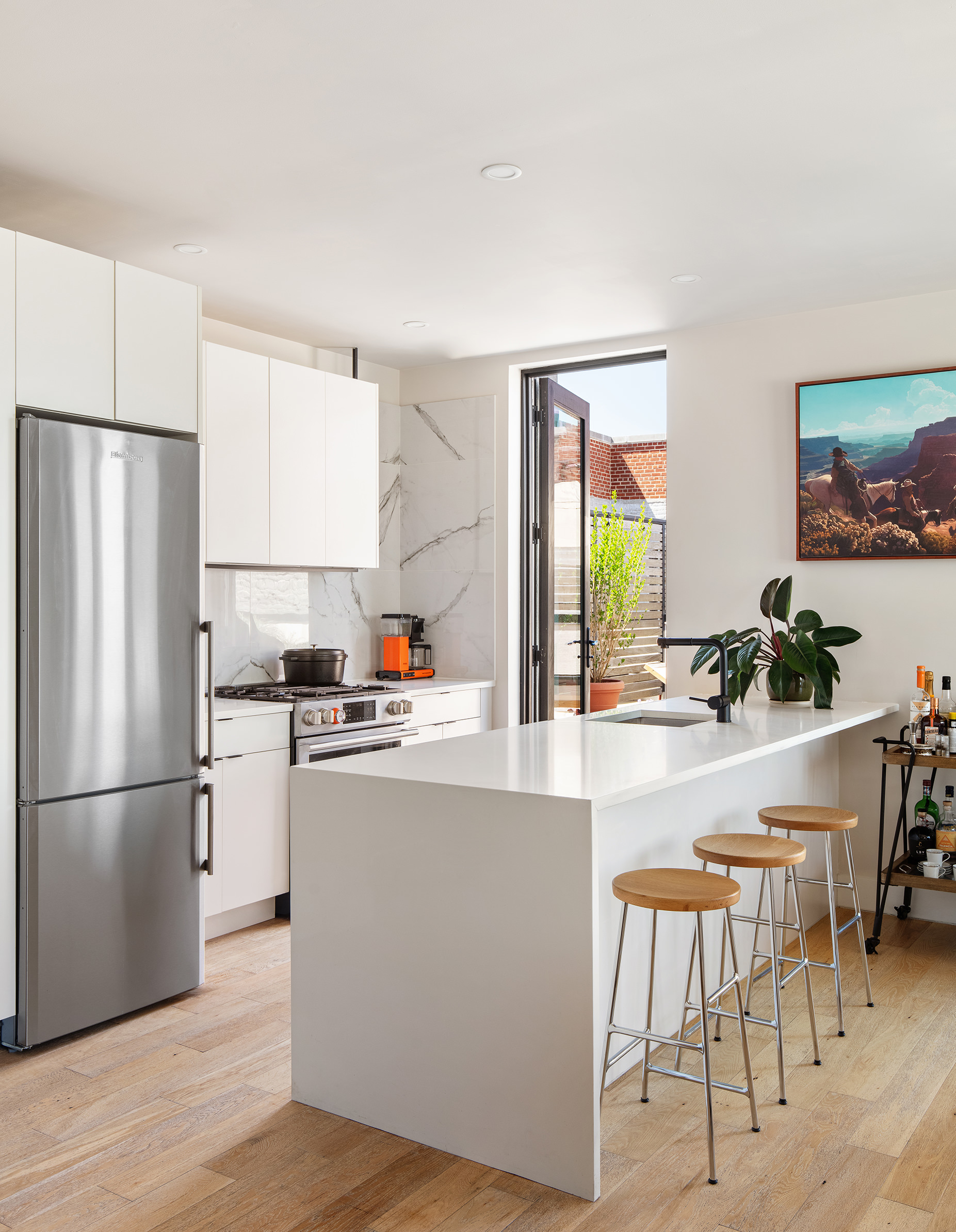 707 Willoughby Avenue, Unit 6B Brooklyn, NY 11206 - Photo 6 of 17 a kitchen with kitchen island a stove a refrigerator and a dining table with wooden floor