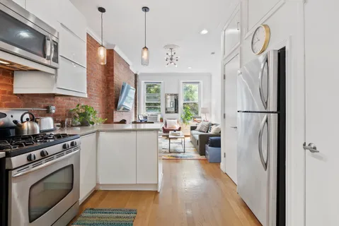 a kitchen with a refrigerator a stove a sink dishwasher a oven with white cabinets and wooden floor