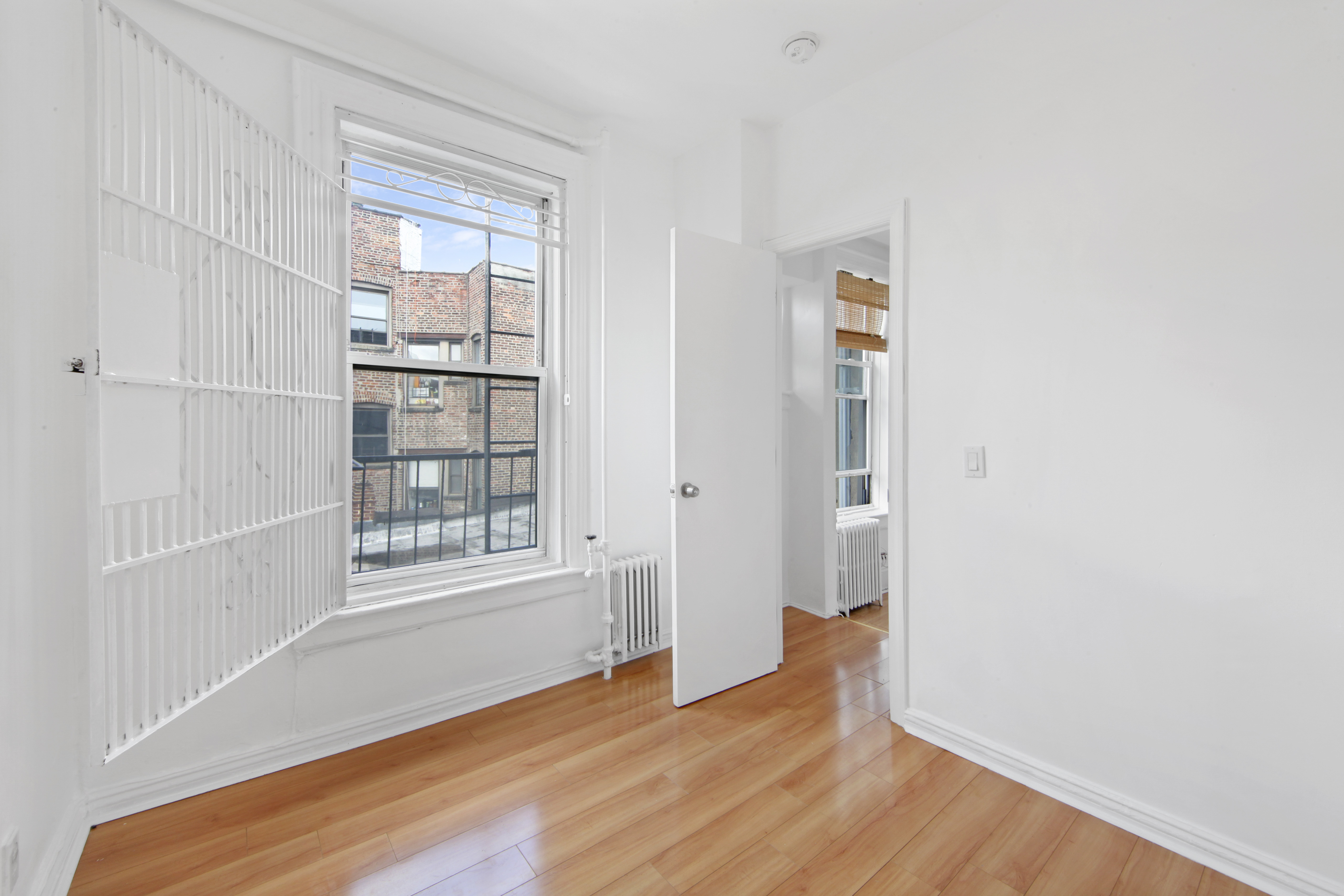 150 Sullivan Street, Unit 37 Manhattan, NY 10012 - Photo 8 of 12 an empty room with wooden floor and windows