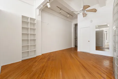 a view of empty room with wooden floor and fan