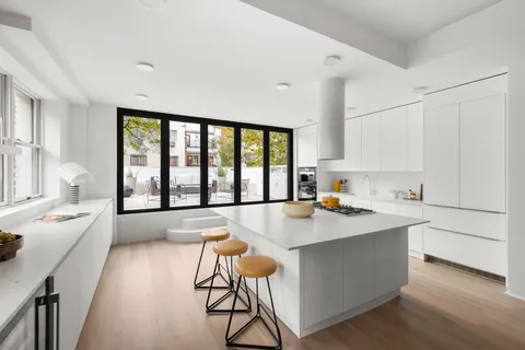 a open kitchen with stainless steel appliances granite countertop a stove a sink and white cabinets with wooden floor