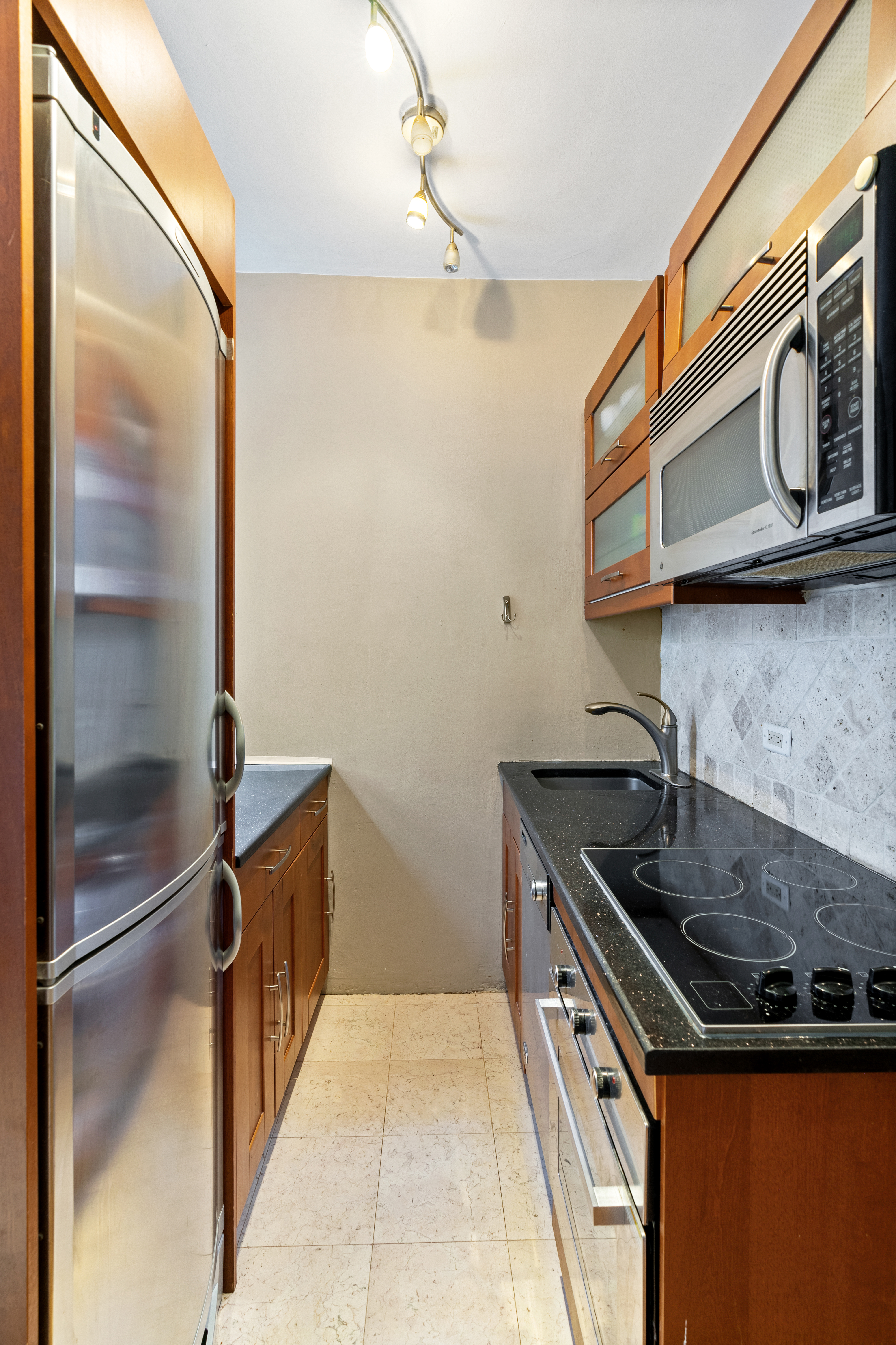 348 West 56th Street, Unit 5B Manhattan, NY 10019 - Photo 3 of 4 a kitchen with stainless steel appliances granite countertop a sink and a cabinets