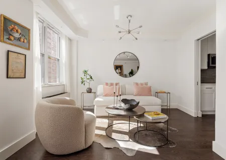 a living room with furniture a chandelier and wooden floor
