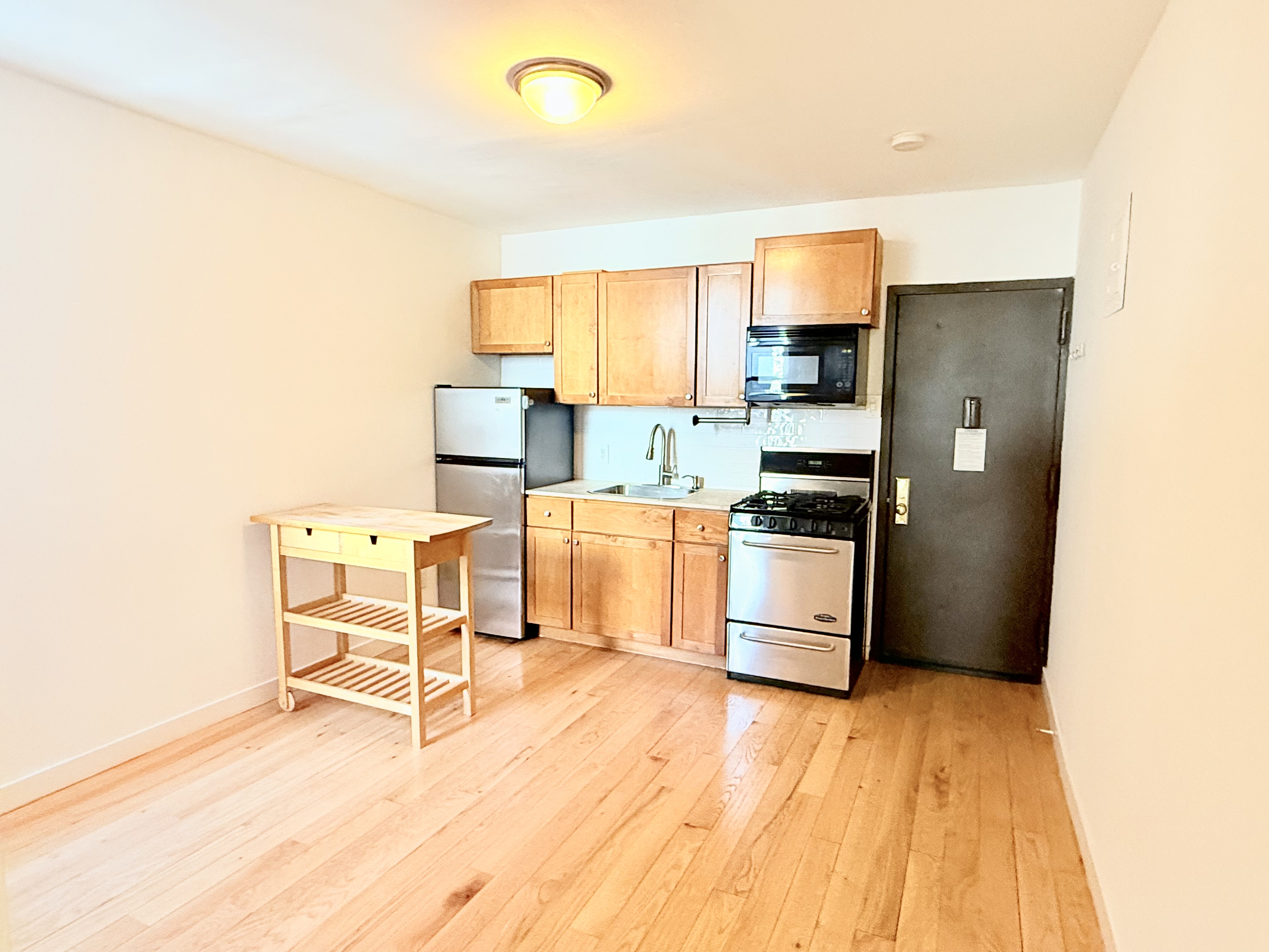 245 West 115th Street, Unit 16 Manhattan, NY 10026 - Photo 3 of 10 a kitchen with stainless steel appliances a stove a refrigerator and white cabinets with wooden floor