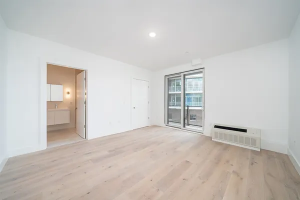 a view of an empty room with wooden floor and a bathroom