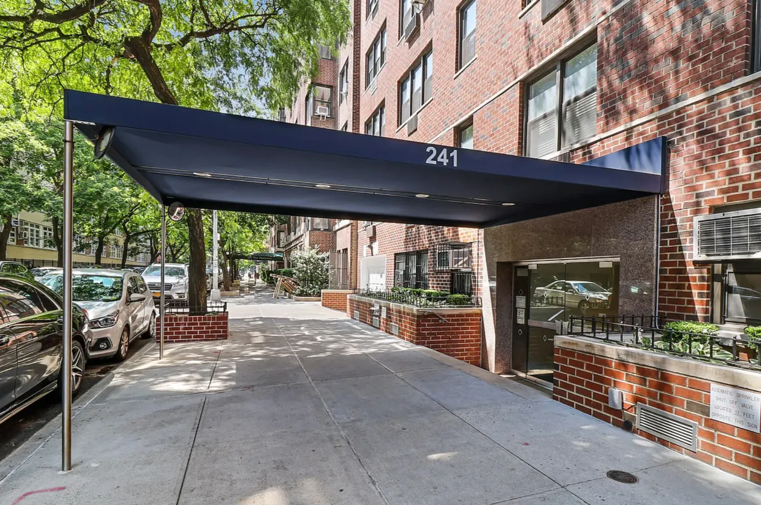 a view of a patio with table and chairs under an umbrella with a large tree