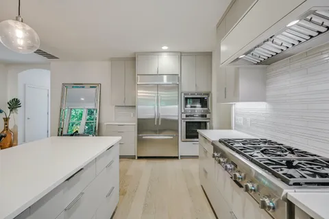 a kitchen with stainless steel appliances a sink a stove a refrigerator cabinets and a window