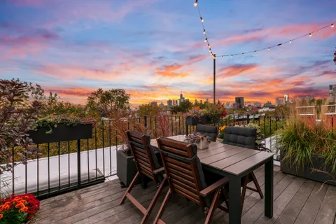 a view of a roof deck with table and chairs with wooden floor and fence