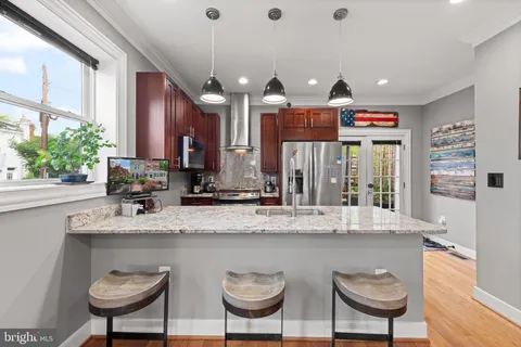 a kitchen with kitchen island granite countertop a sink and a refrigerator