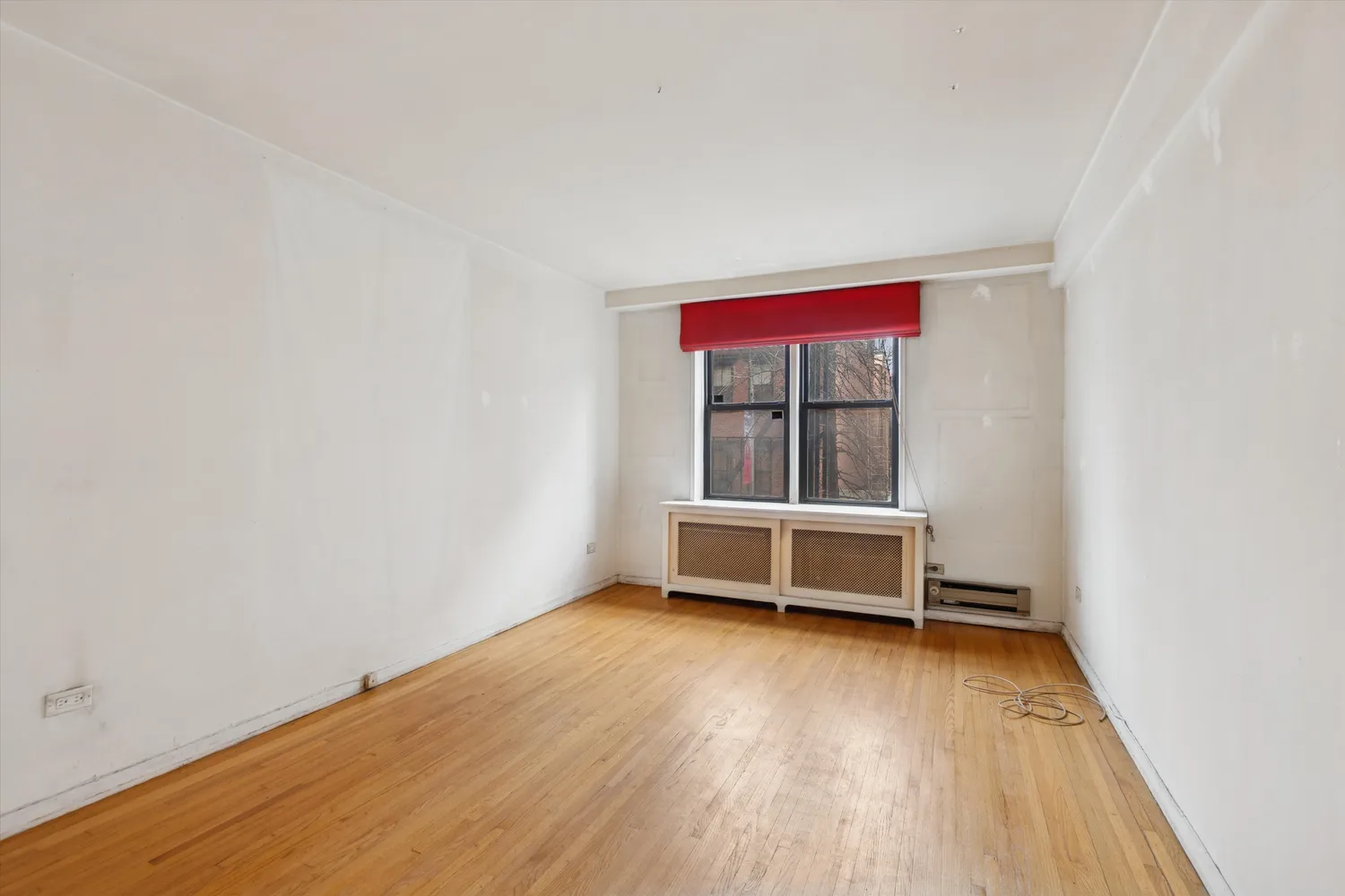 an empty room with a window and wooden floor