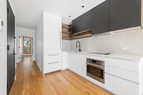 a view of a kitchen with white cabinets and wooden floor