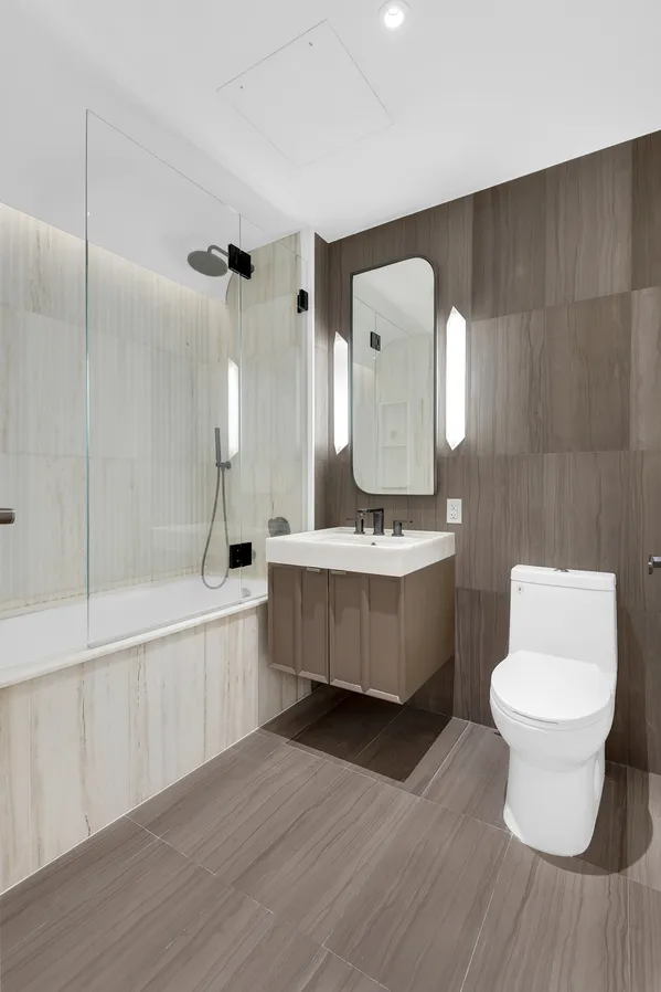 a bathroom with a double vanity sink toilet mirror and bathtub