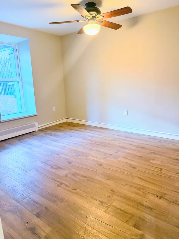 a view of an empty room with wooden floor and a window