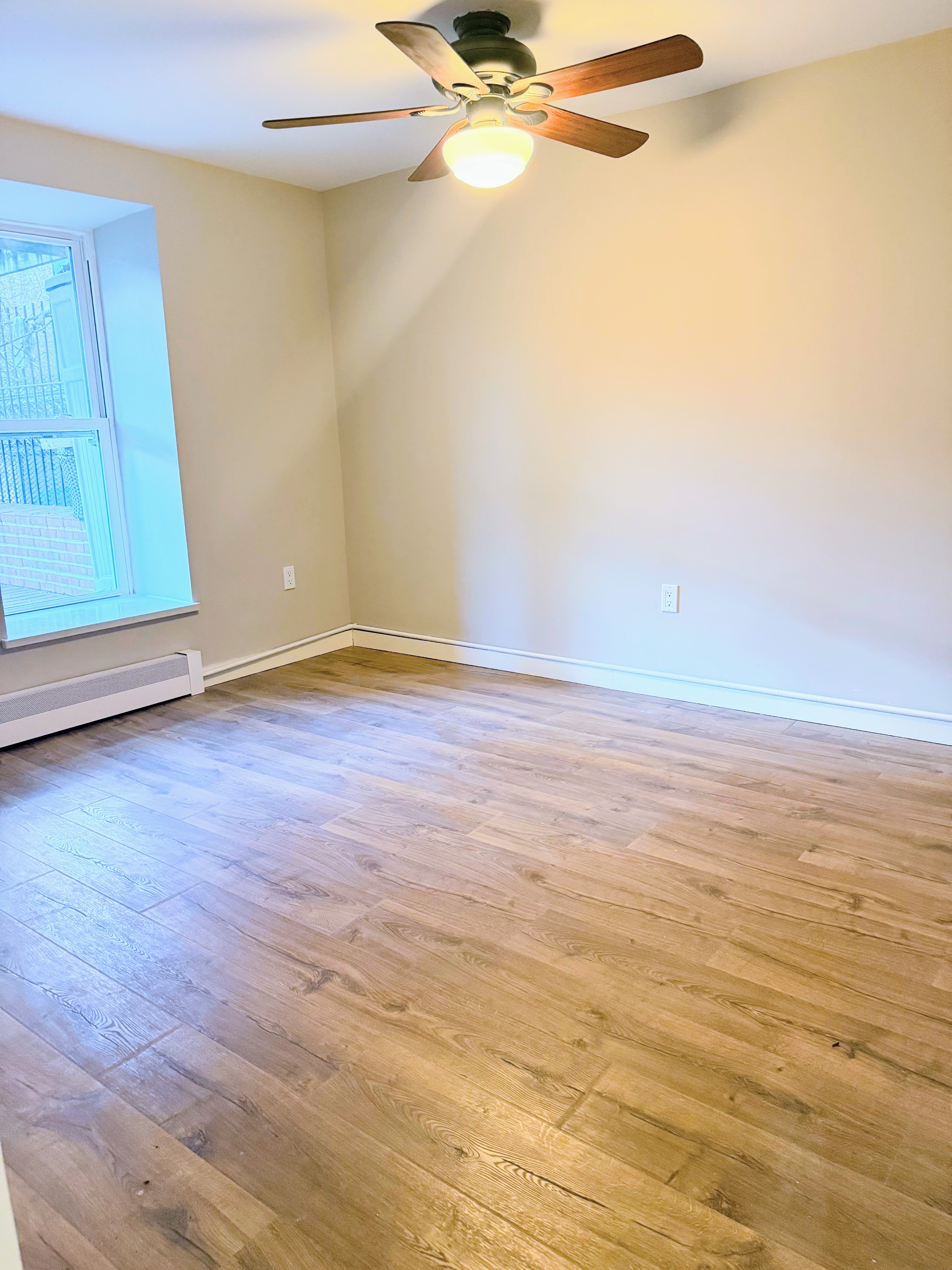 642 West 207th Street, Unit 1 Manhattan, NY 10034 - Photo 6 of 11 a view of an empty room with wooden floor and a window