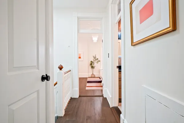 a view of a hallway with wooden floor and cabinet