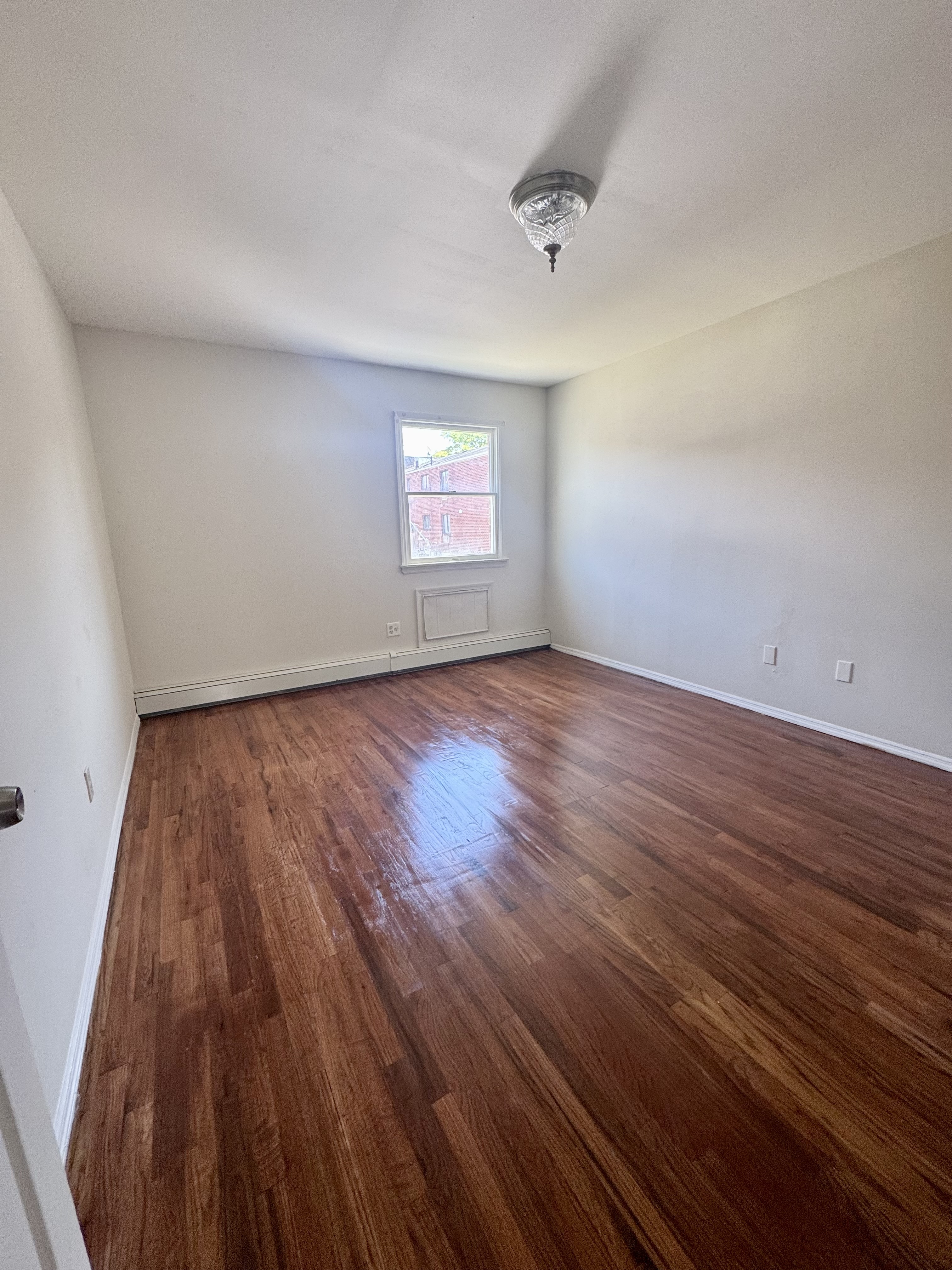 156-17 76th Street, Unit 1 Queens, NY 11414 - Photo 7 of 12 an empty room with wooden floor and windows