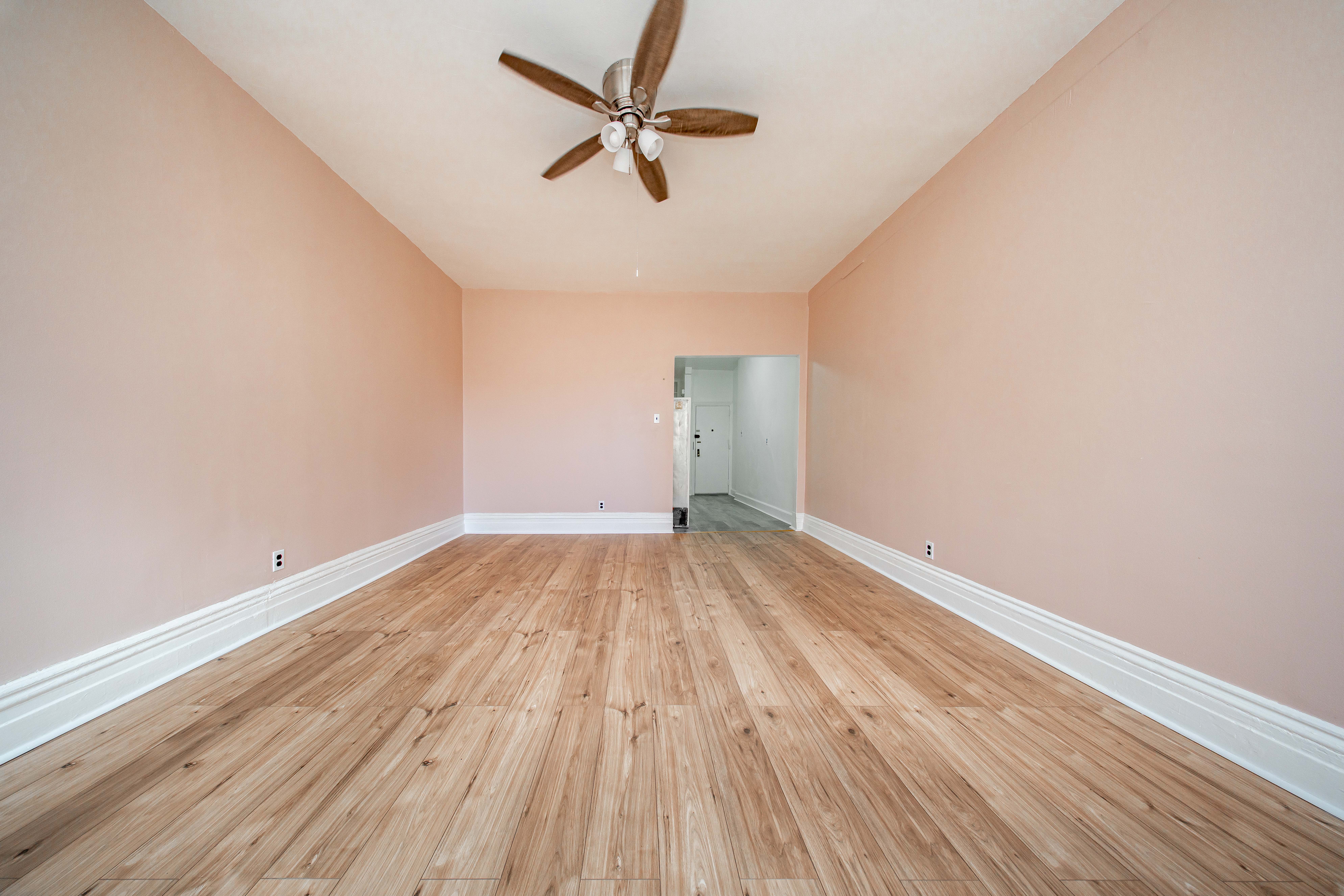 22-17 Astoria Boulevard, Unit 2W Queens, NY 11102 - Photo 4 of 10 an empty room with wooden floor and a ceiling fan