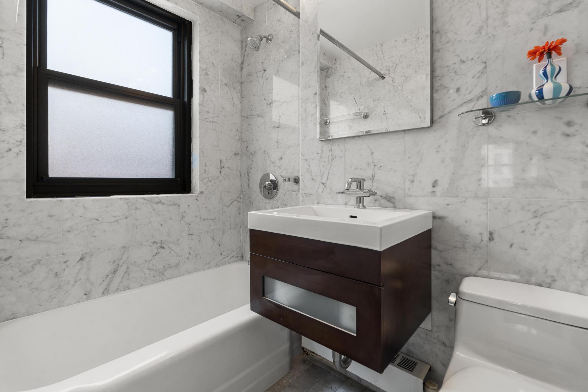 201 East 21st Street, Unit 8E Manhattan, NY 10010 - Photo 6 of 9 a bathroom with a sink toilet a mirror and bathtub