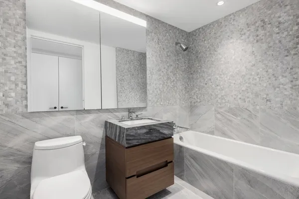 a bathroom with a granite countertop sink a toilet and bathtub