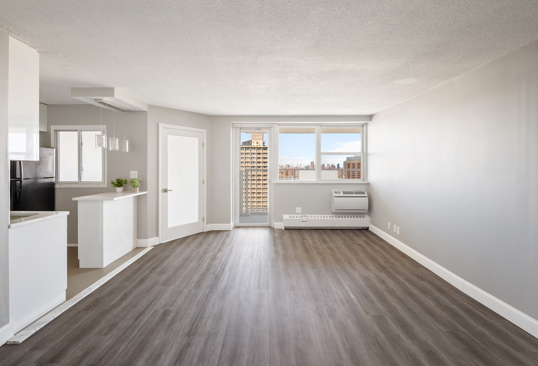 75 Henry Street, Unit 21C Brooklyn, NY 11201 - Photo 1 of 11 a view of a kitchen and an empty room with wooden floor