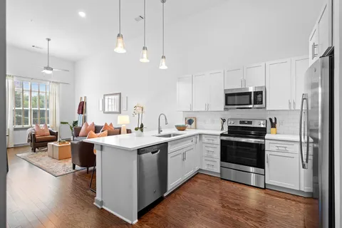 a open kitchen with stainless steel appliances granite countertop a stove top oven a refrigerator a sink and a fireplace with wooden floor