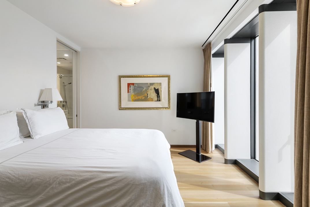 551 West 21st Street, Unit 4D Manhattan, NY 10011 - Photo 7 of 16 a bedroom with a bed and a flat screen tv