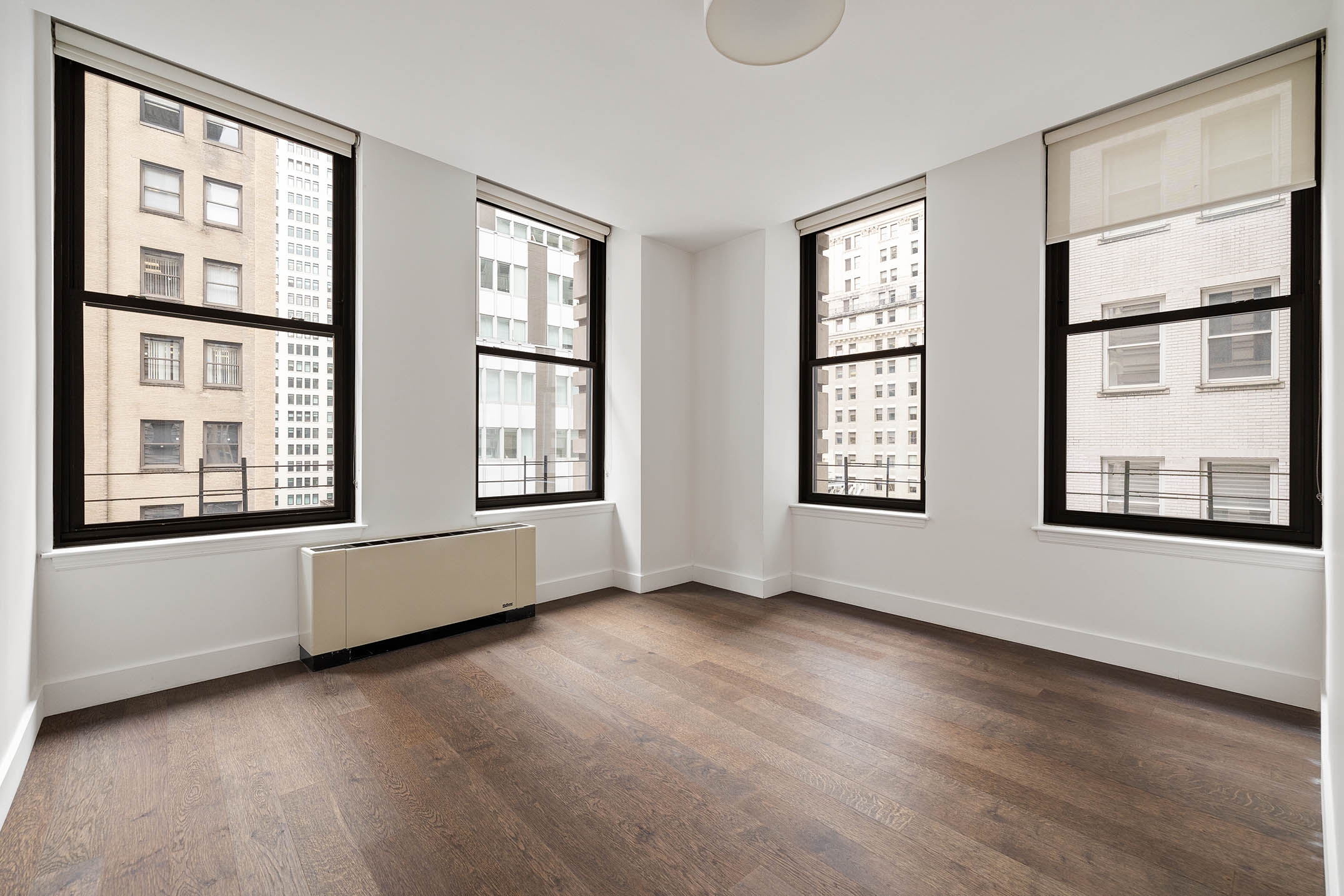 25 Broad Street, Unit 16I Manhattan, NY 10004 - Photo 12 of 23 a view of an empty room with wooden floor and windows