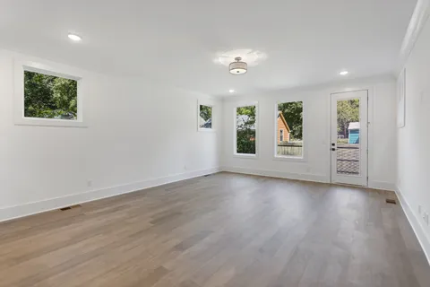 a large white kitchen with stainless steel appliances kitchen island a large counter top a stove and a refrigerator with wooden floor