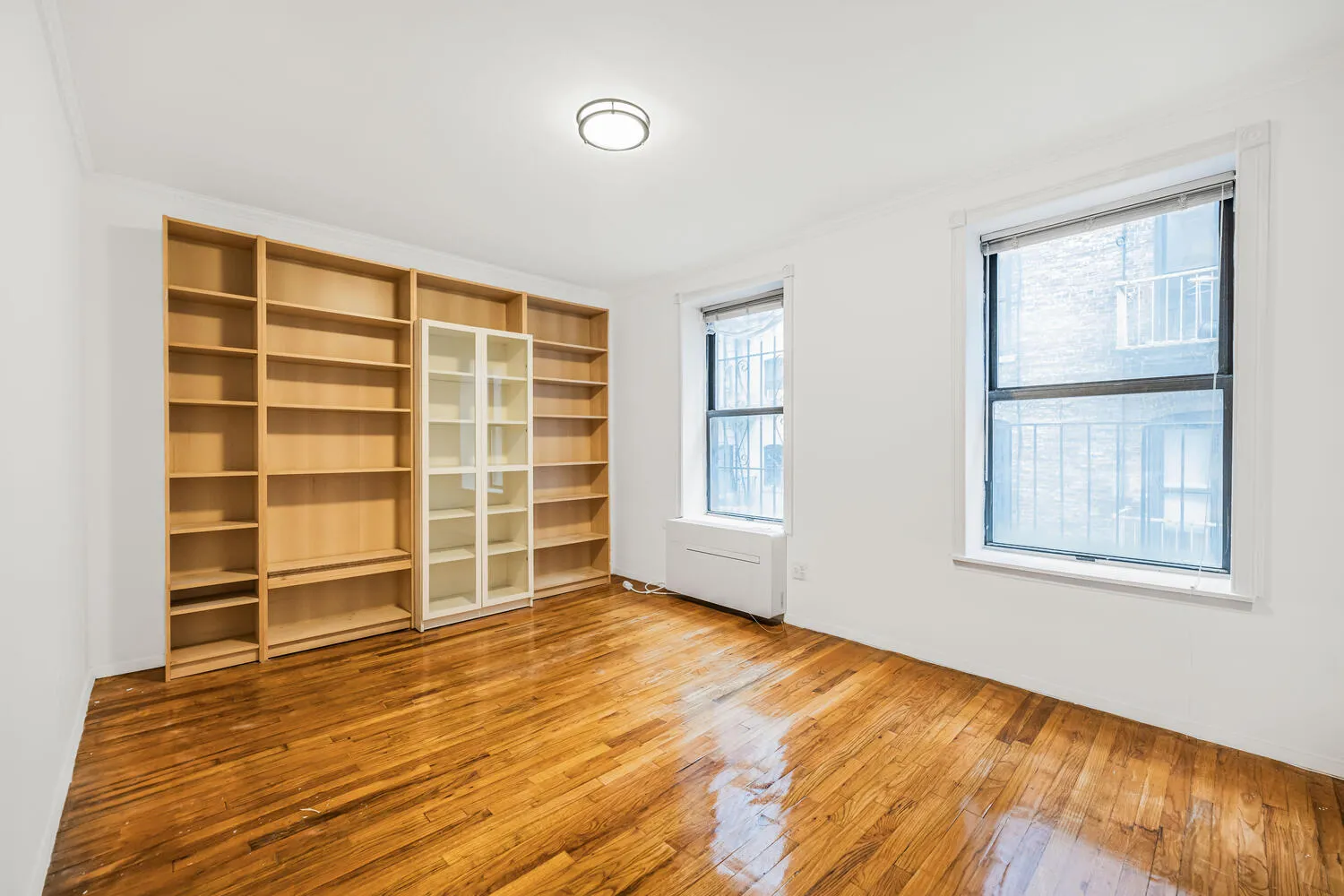 a view of an empty room with a window and wooden floor