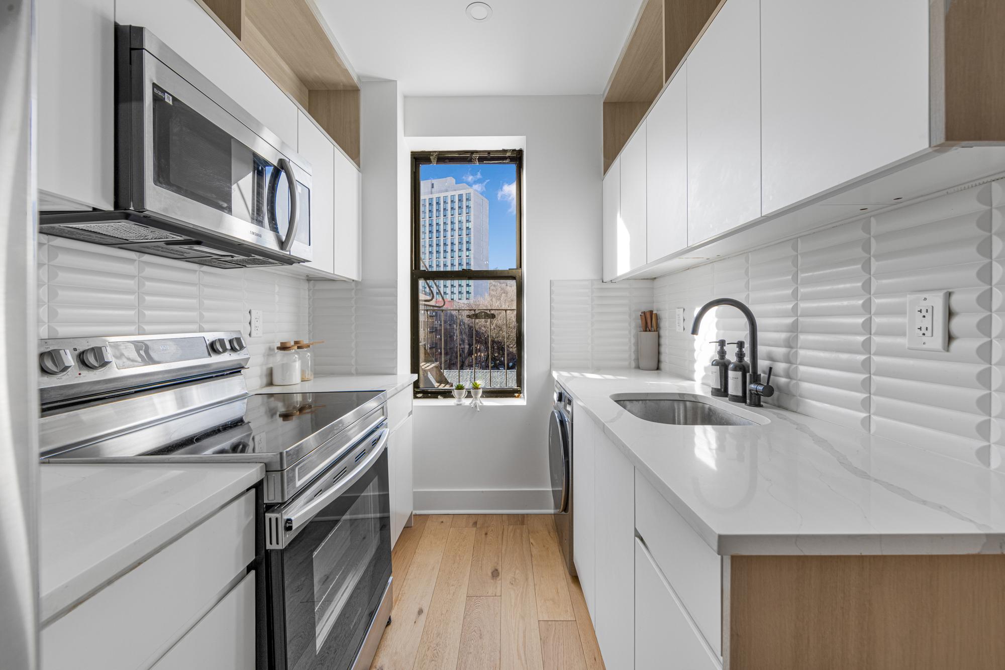 78 Thayer Street, Unit E5 Manhattan, NY 10040 - Photo 4 of 8 a kitchen with stainless steel appliances a sink stove and cabinets