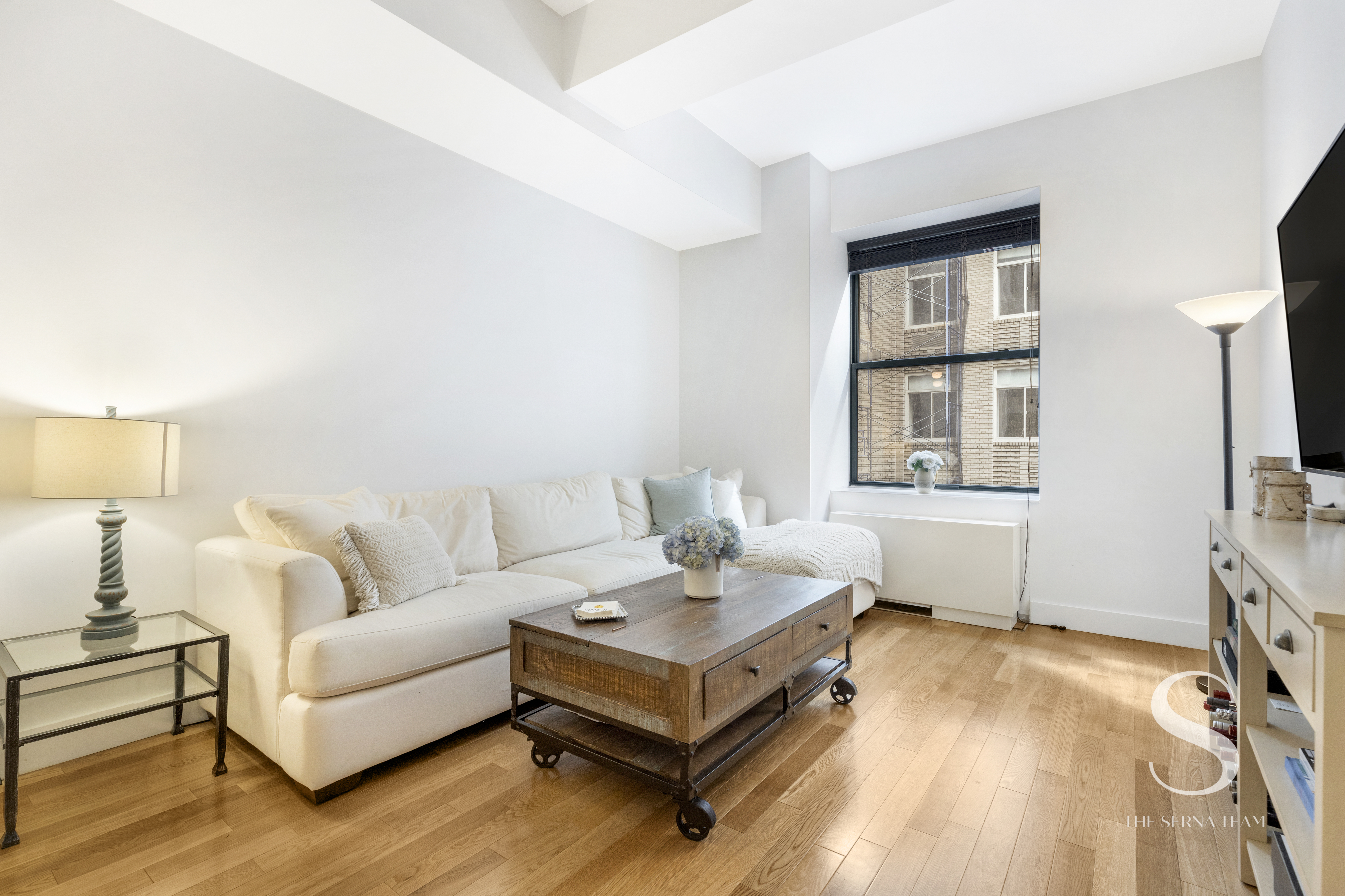 a living room with furniture a flat screen tv and a table
