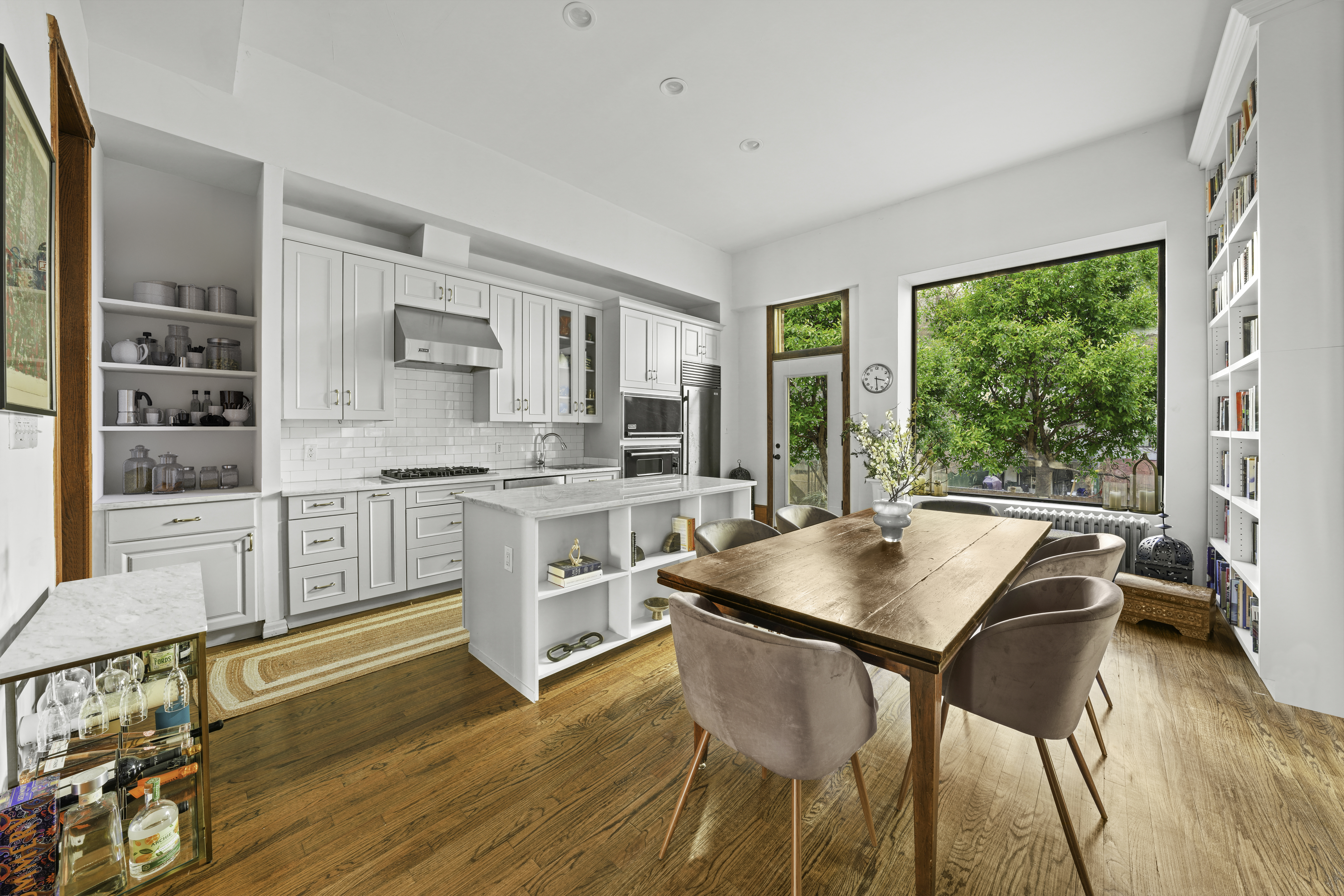 a kitchen with stainless steel appliances granite countertop a stove top oven a sink and a dining table with wooden floor