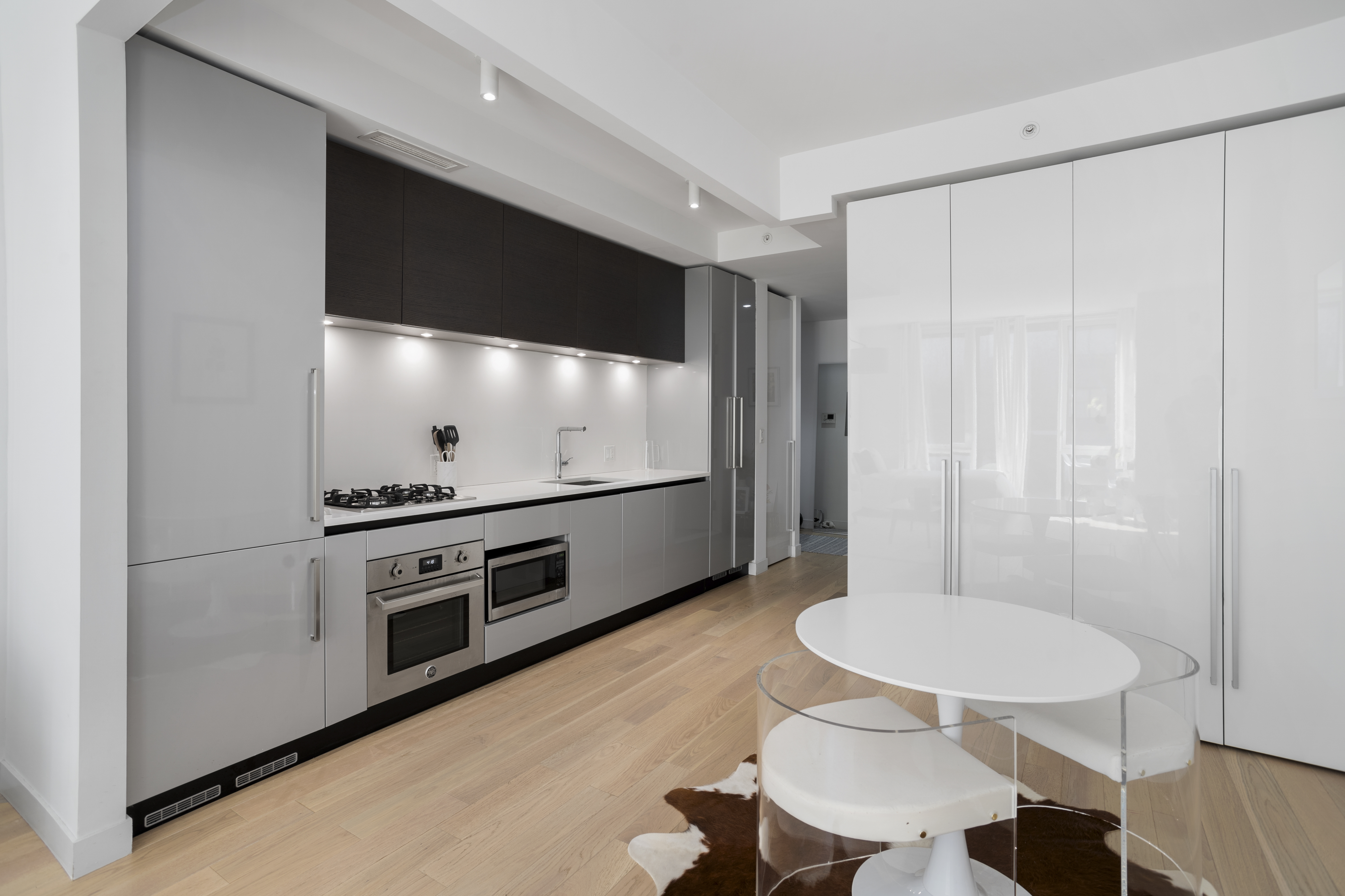 540 West 49th Street, Unit 405S Manhattan, NY 10019 - Photo 3 of 12 a kitchen with stainless steel appliances a stove a table and chairs