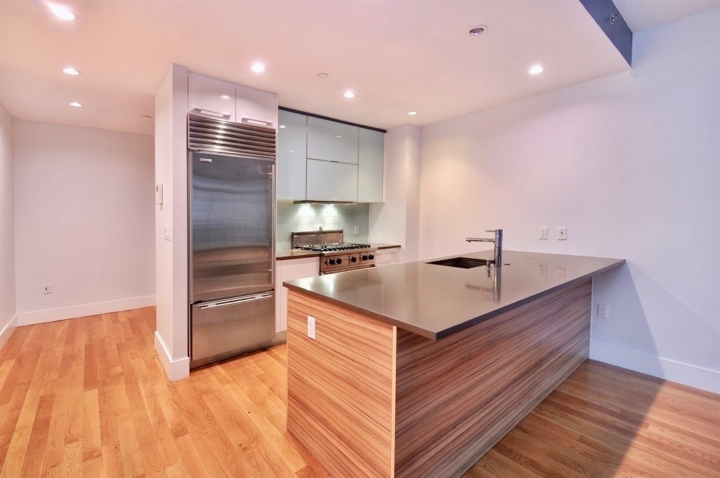 117 West 123rd Street, Unit 4B Manhattan, NY 10027 - Photo 6 of 16 a kitchen with kitchen island a sink appliances and cabinets
