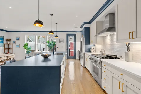 a kitchen with stainless steel appliances granite countertop a sink a stove and a wooden floors