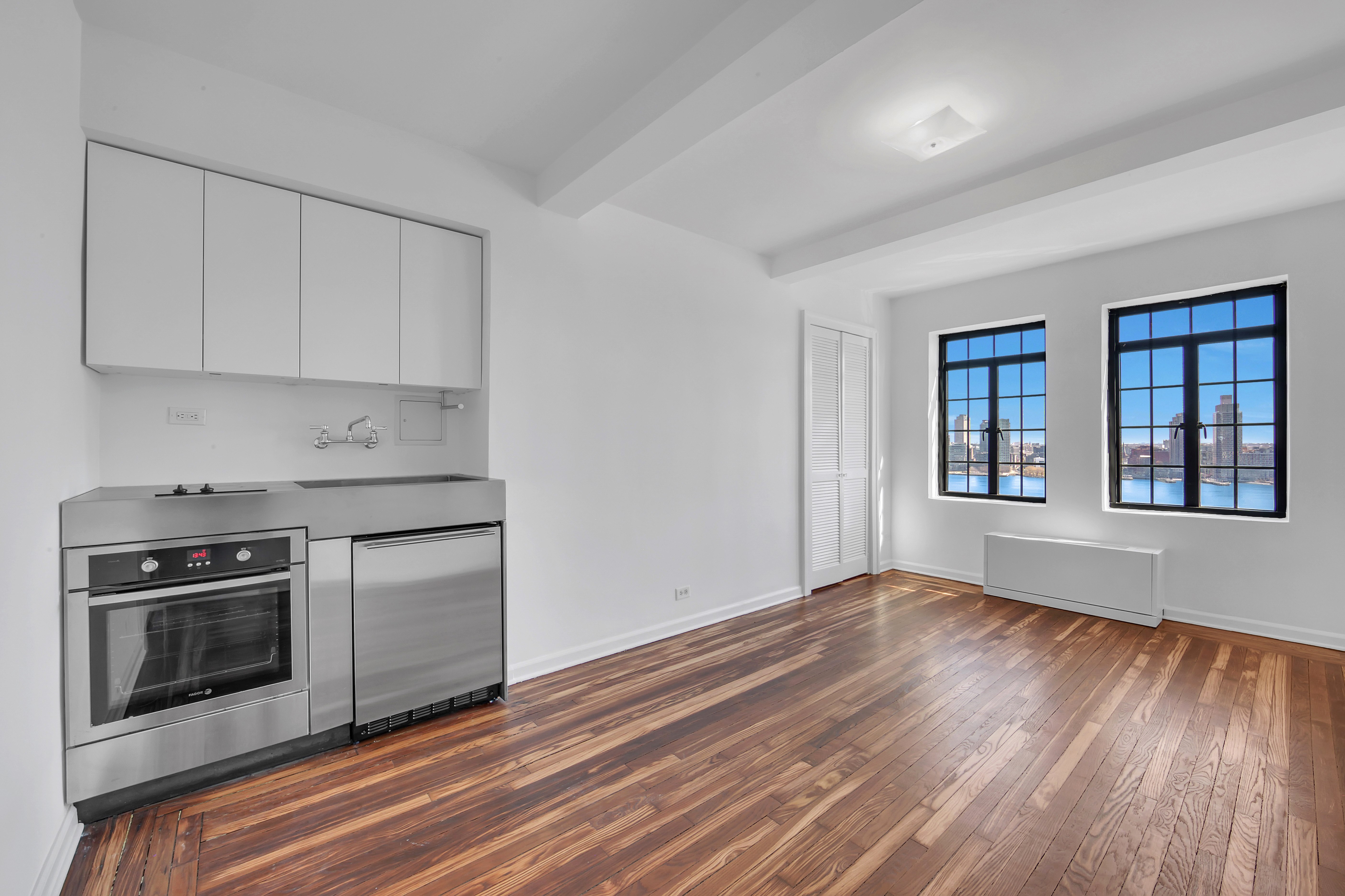 5 Tudor City Place, Unit 1126 Manhattan, NY 10017 - Photo 2 of 20 a view of kitchen with granite countertop wooden floor stainless steel appliances and window