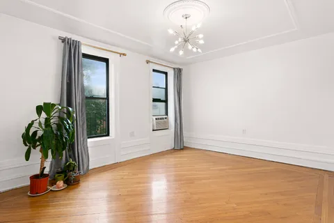 a view of an empty room with window and wooden floor