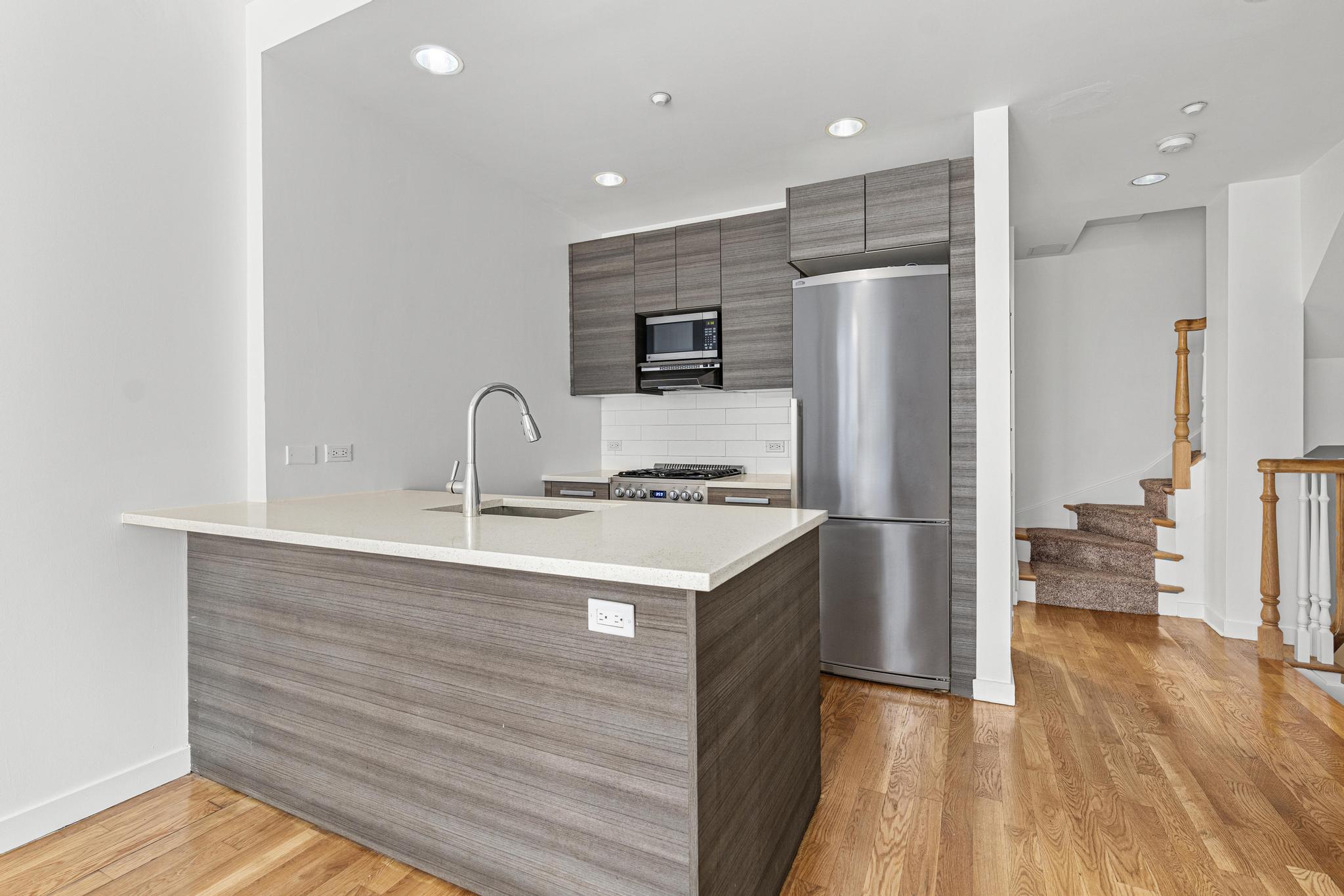 a kitchen with stainless steel appliances granite countertop a sink a stove and a refrigerator