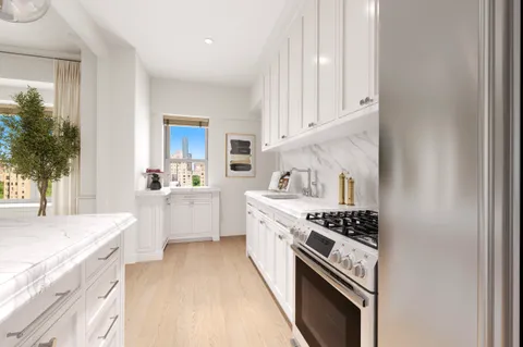 a kitchen with stainless steel appliances a sink dishwasher stove and white cabinets with wooden floor