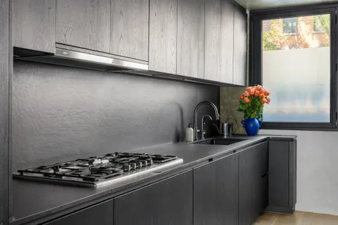 a close view of a sink a stove and cabinets in a kitchen
