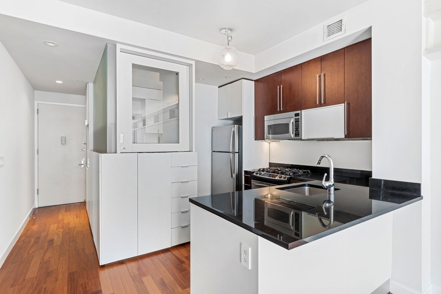100 Jay Street, Unit 21J Brooklyn, NY 11201 - Photo 2 of 13 a kitchen with stainless steel appliances granite countertop a sink a microwave a refrigerator and wooden cabinets