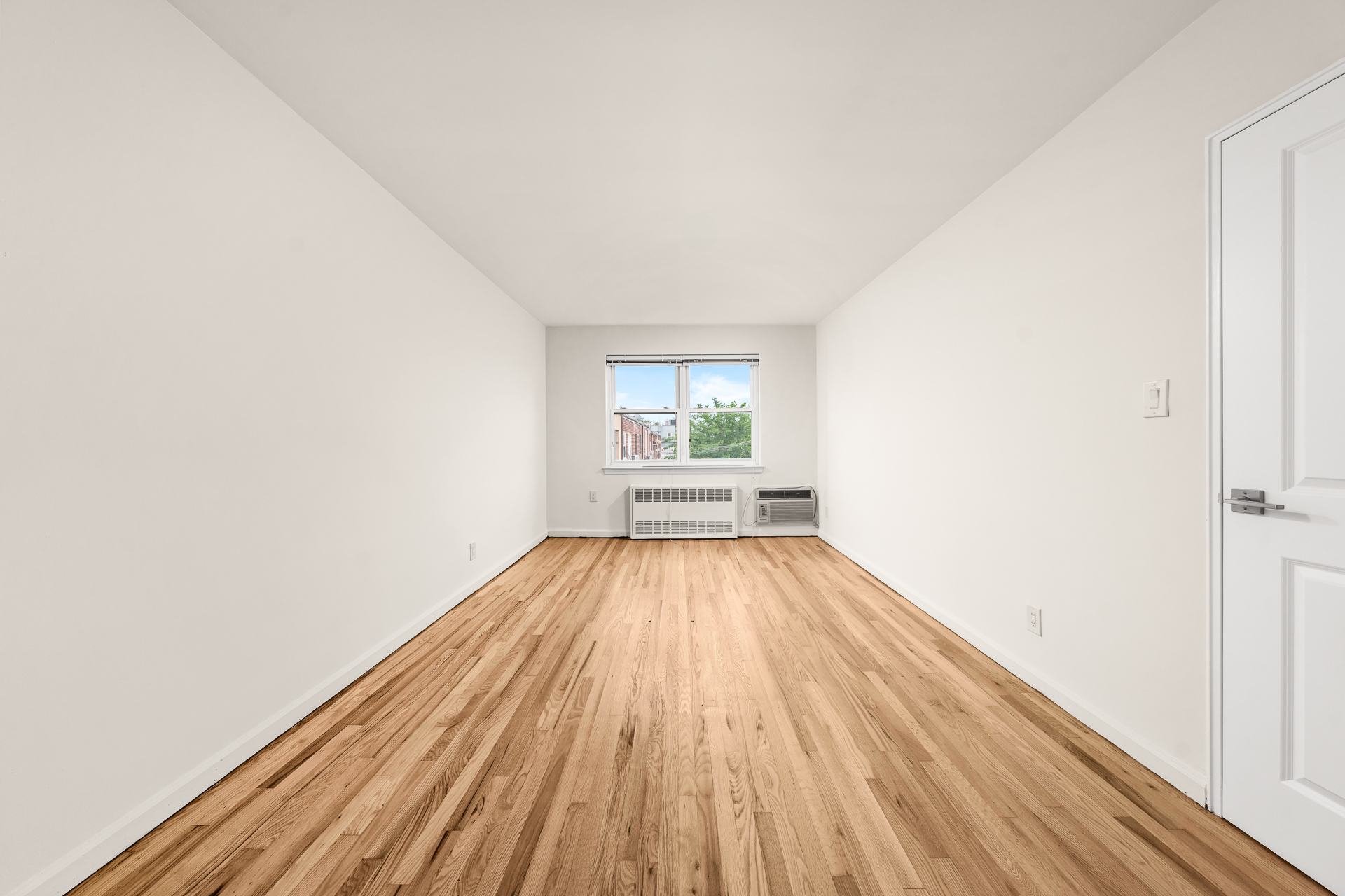 412 Fairview Avenue, Unit 1 Queens, NY 11385 - Photo 6 of 9 an empty room with wooden floor and windows