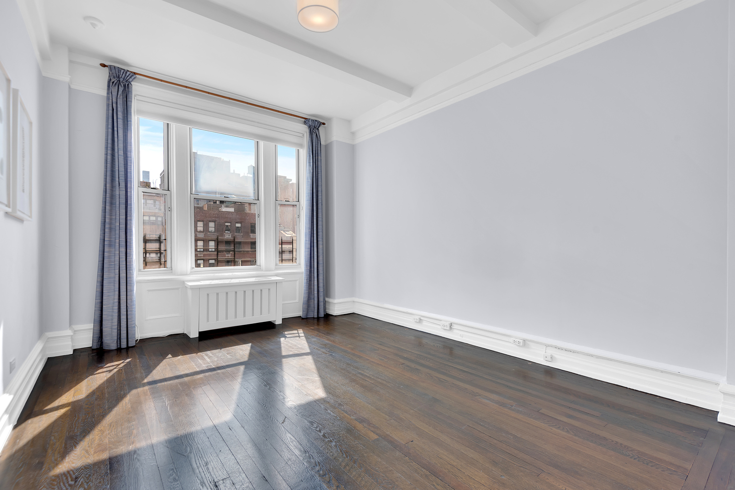 122 East 82nd Street, Unit 8C Manhattan, NY 10028 - Photo 8 of 15 an empty room with wooden floor and windows