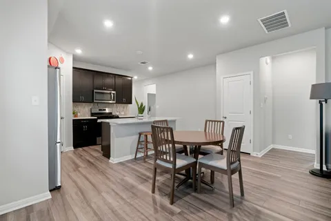 a kitchen with a table chairs refrigerator and microwave