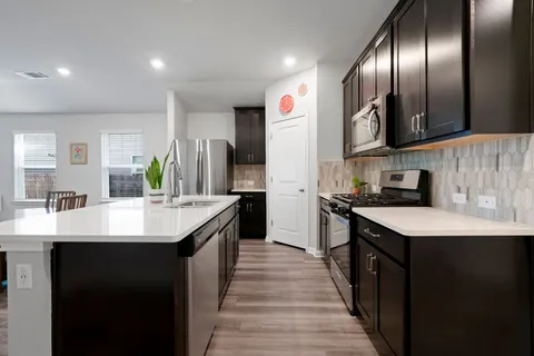 a kitchen with stainless steel appliances granite countertop a sink a stove and a refrigerator