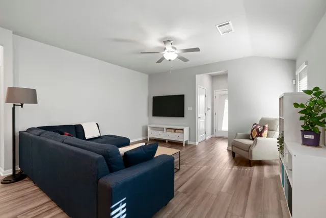 a living room with furniture ceiling fan and a flat screen tv